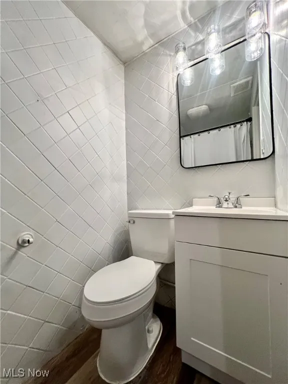 Full bathroom featuring tile walls, wood finished floors, and vanity