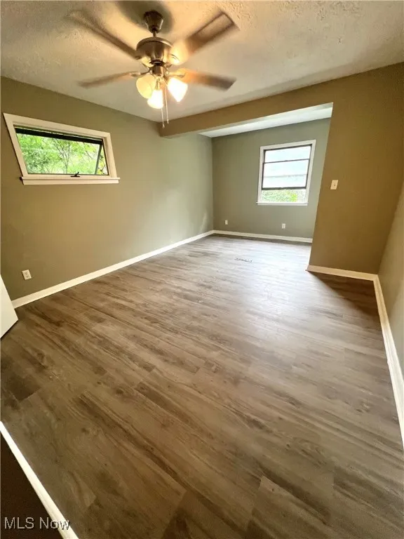Spare room with a textured ceiling, a ceiling fan, and wood finished floors