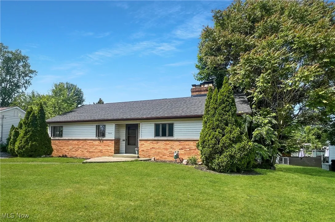 Ranch-style house featuring brick siding, a front lawn, a chimney, and roof with shingles
