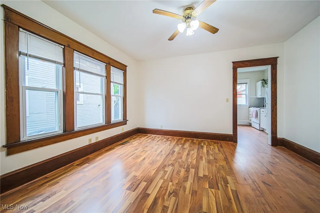 Empty room with wood finished floors, baseboards, and ceiling fan