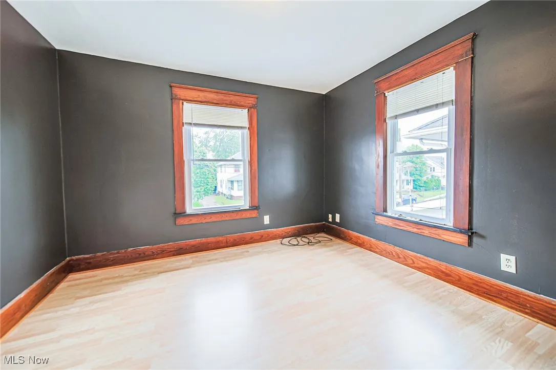 Empty room with wood finished floors, healthy amount of natural light, and baseboards