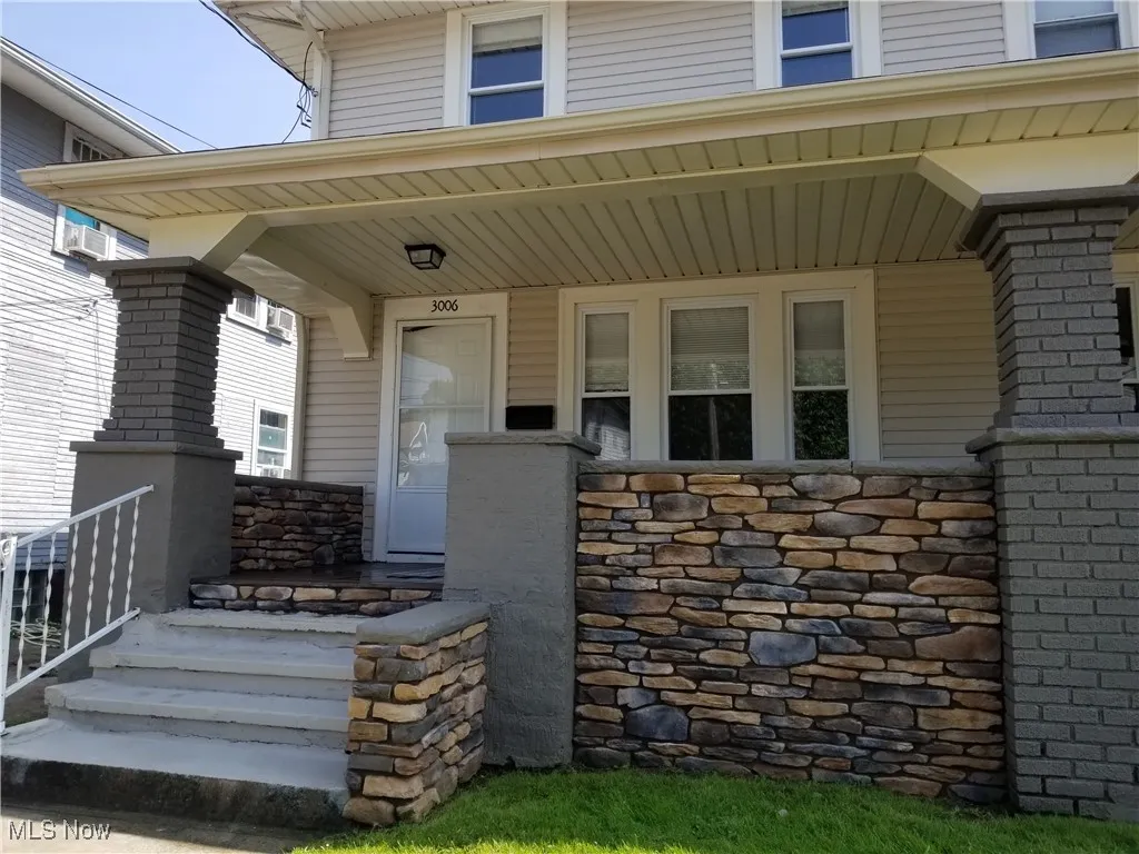 View of exterior entry featuring a porch and stone siding