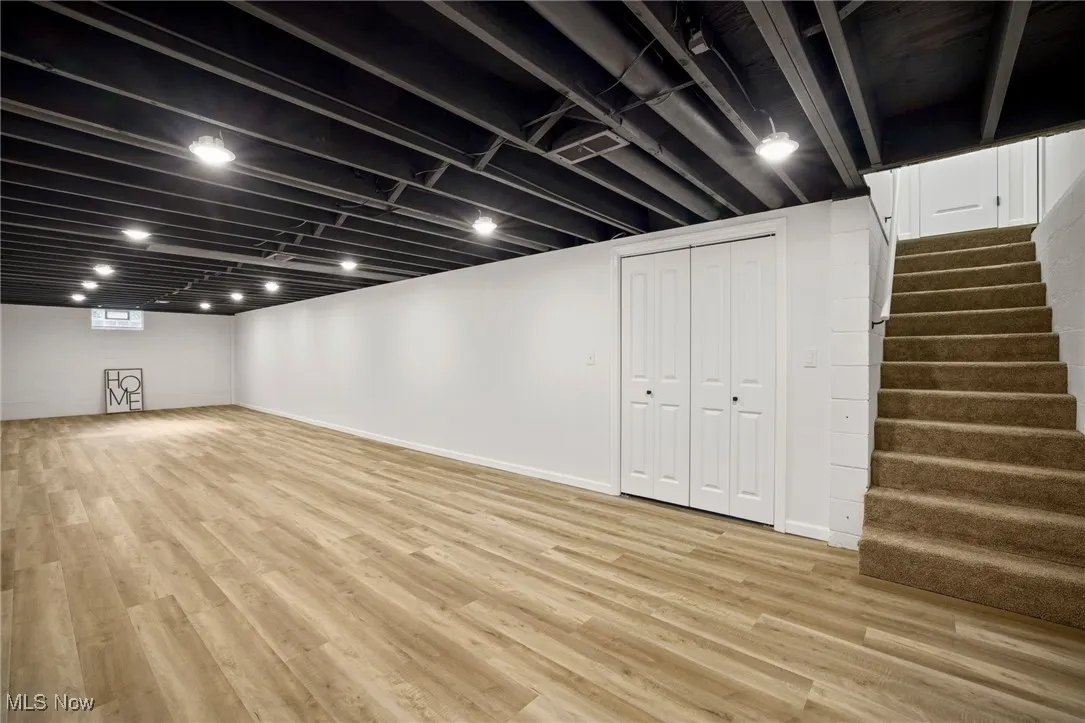 Basement with stairway and light wood finished floors