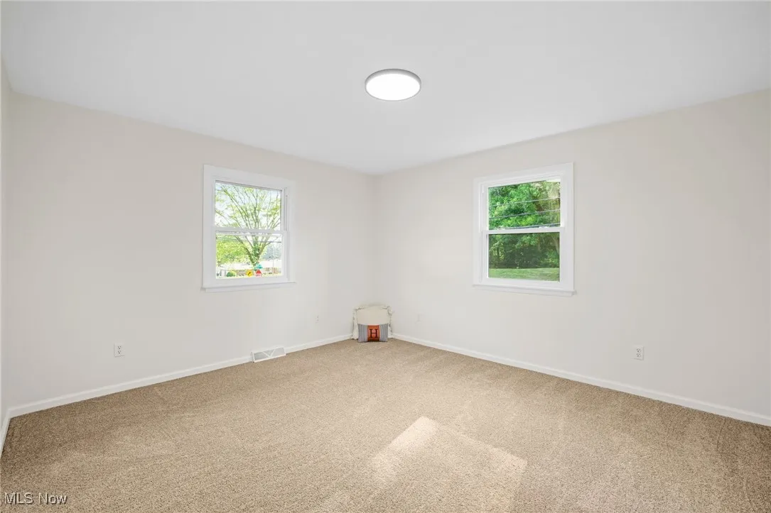 Carpeted spare room featuring healthy amount of natural light