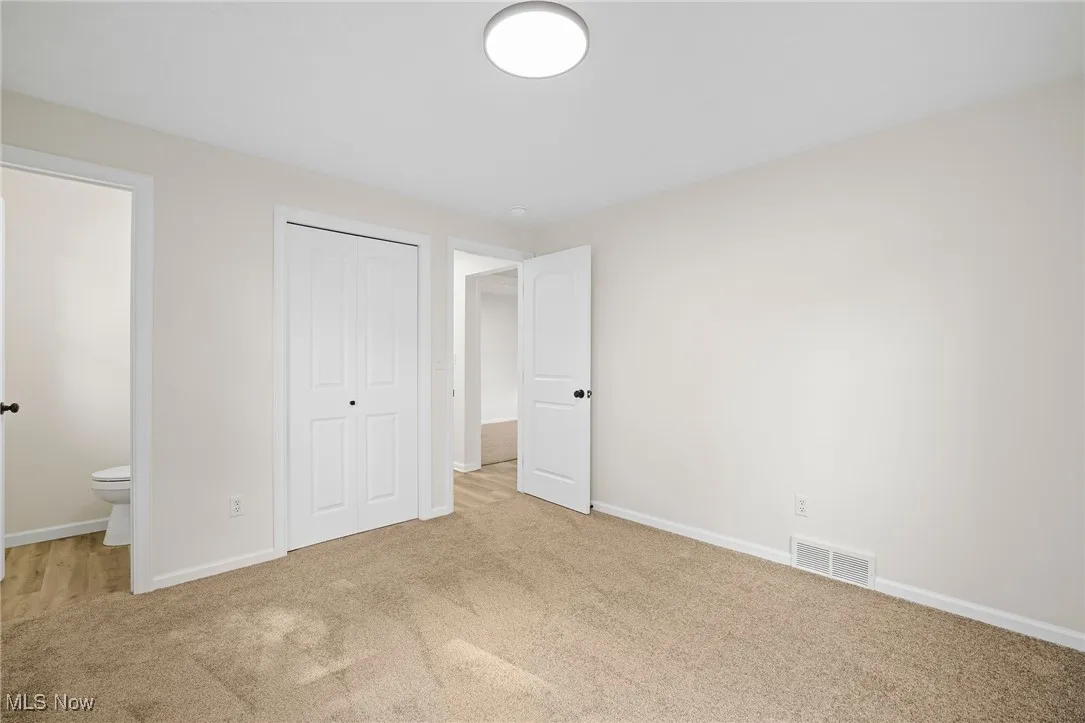 Unfurnished bedroom featuring carpet, a closet, and ensuite bathroom