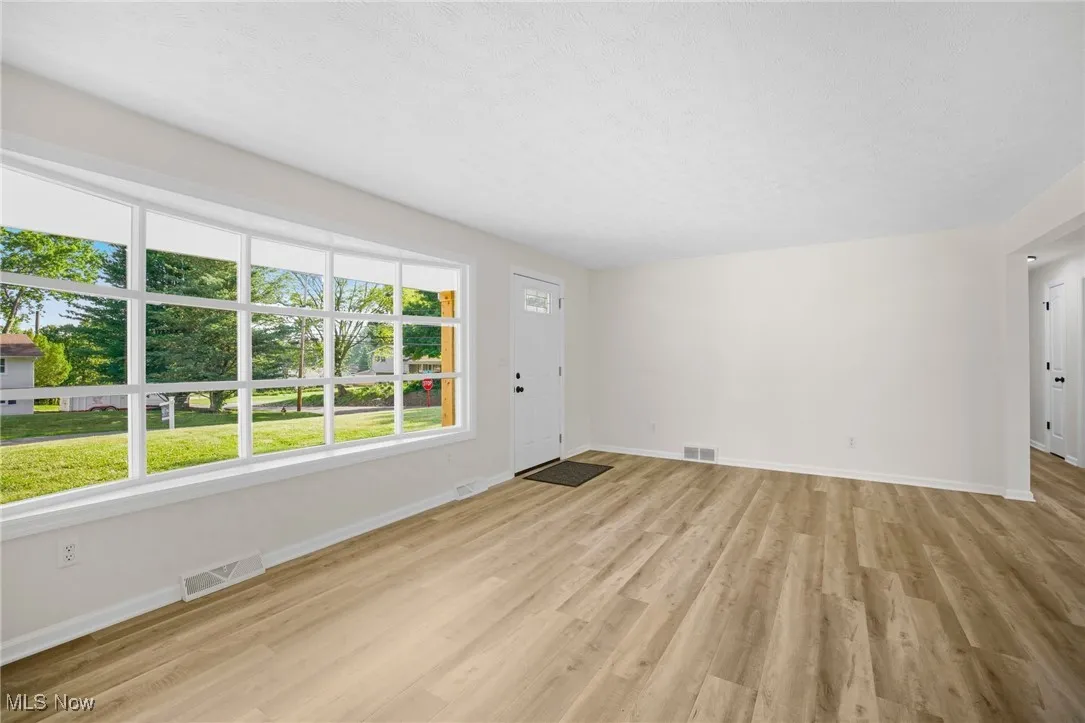Unfurnished living room featuring baseboards and light wood-style flooring