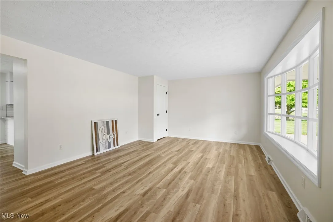 Empty room featuring light wood-style flooring and a textured ceiling