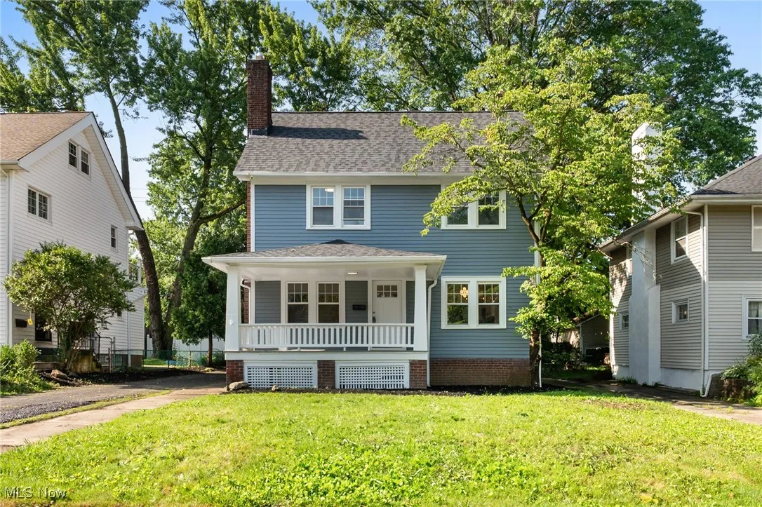 Traditional style home with covered porch, a front lawn, a chimney, and a shingled roof