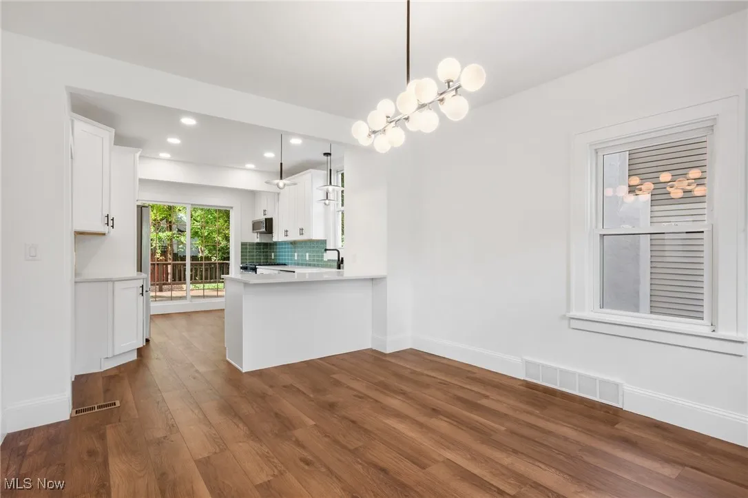Kitchen featuring stainless steel microwave, white cabinetry, recessed lighting, and light countertops