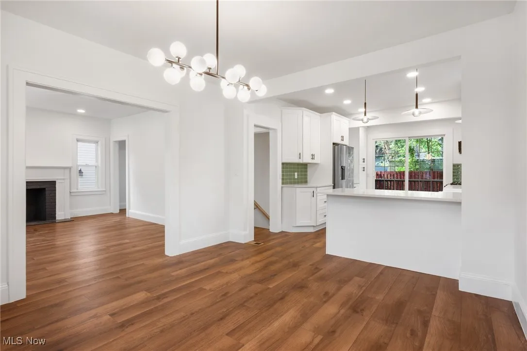 Unfurnished living room with recessed lighting, a chandelier, and a brick fireplace