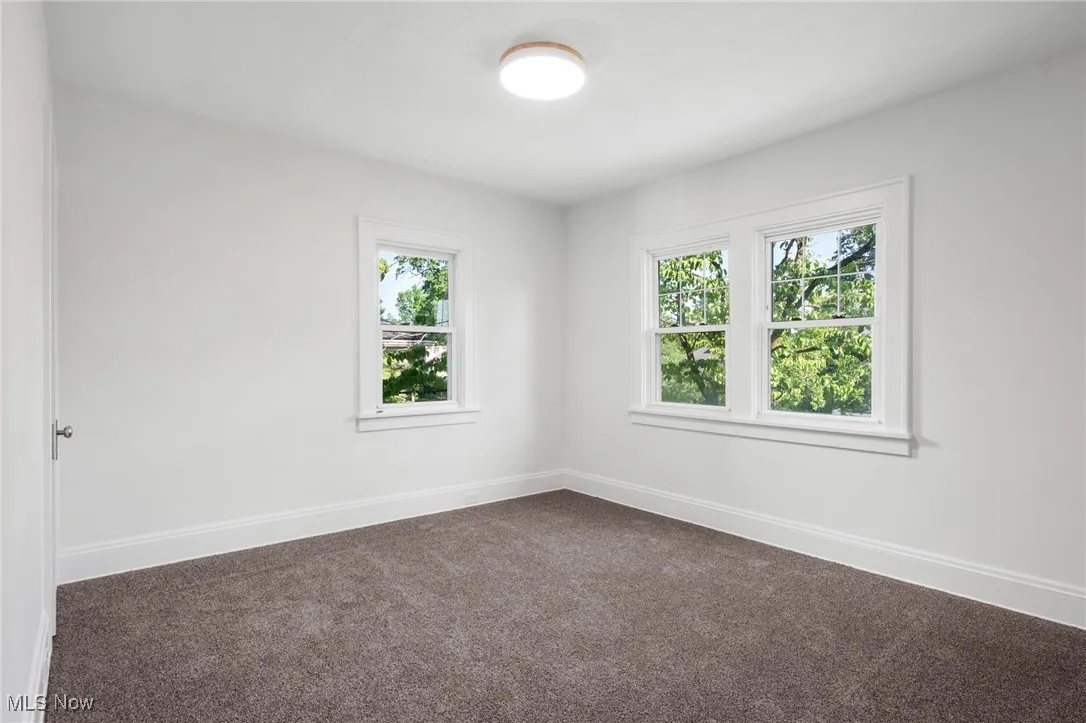 Spare room featuring dark carpet and baseboards