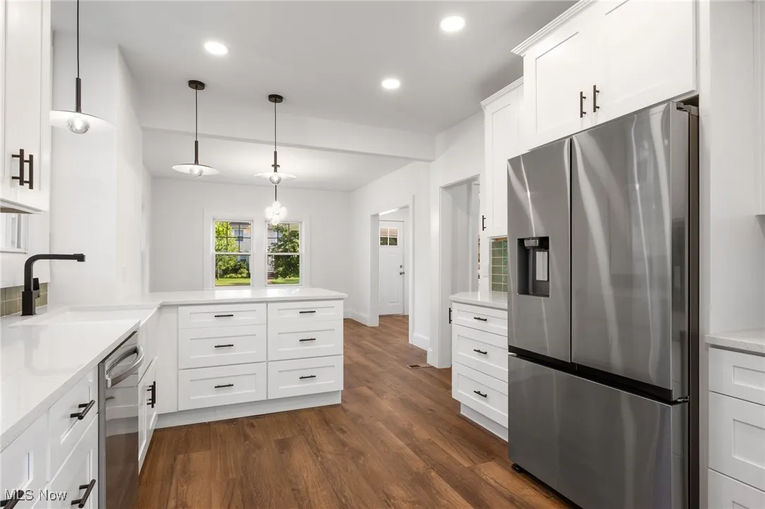 Kitchen with stainless steel appliances, a peninsula, recessed lighting, and white cabinets