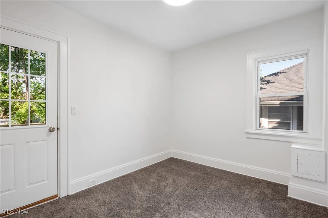 Unfurnished room featuring dark colored carpet and baseboards