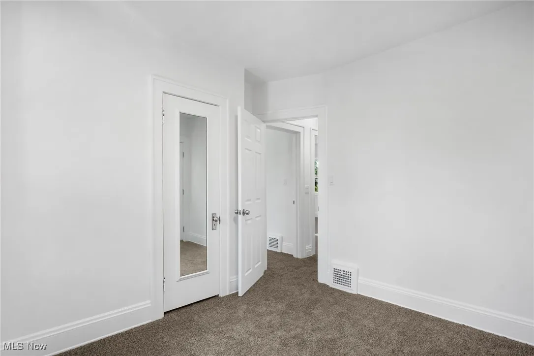 Unfurnished bedroom with dark carpet and baseboards
