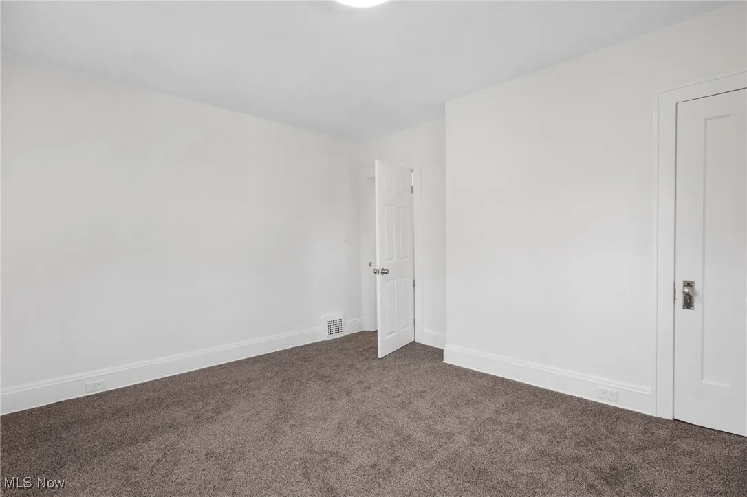 Spare room featuring dark carpet and baseboards