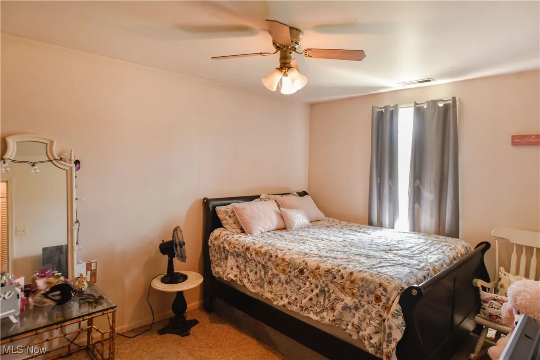 Carpeted bedroom featuring a ceiling fan