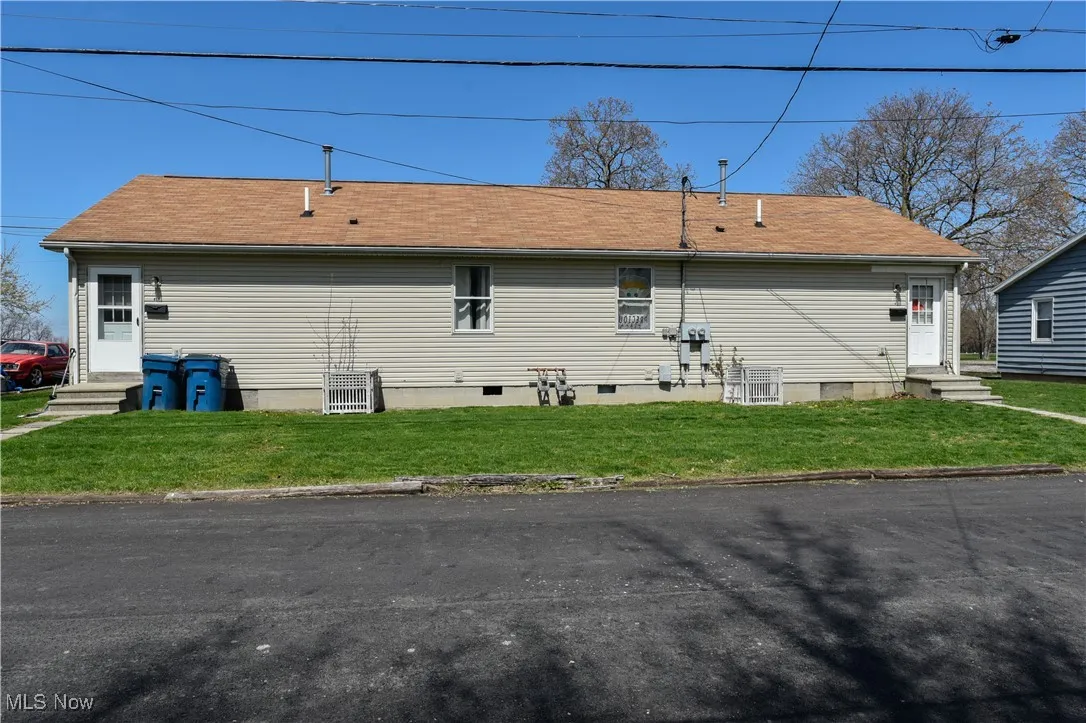 Back of house with entry steps and a yard