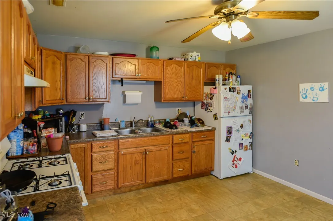Kitchen featuring white appliances, under cabinet range hood, and brown cabinets