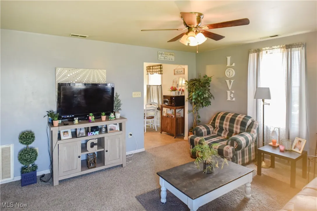 Living area with a ceiling fan and carpet