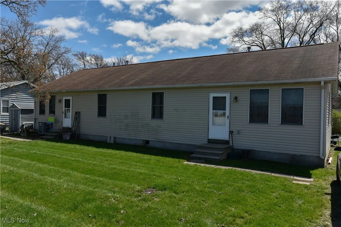 View of front of property featuring entry steps, a front lawn, and roof with shingles