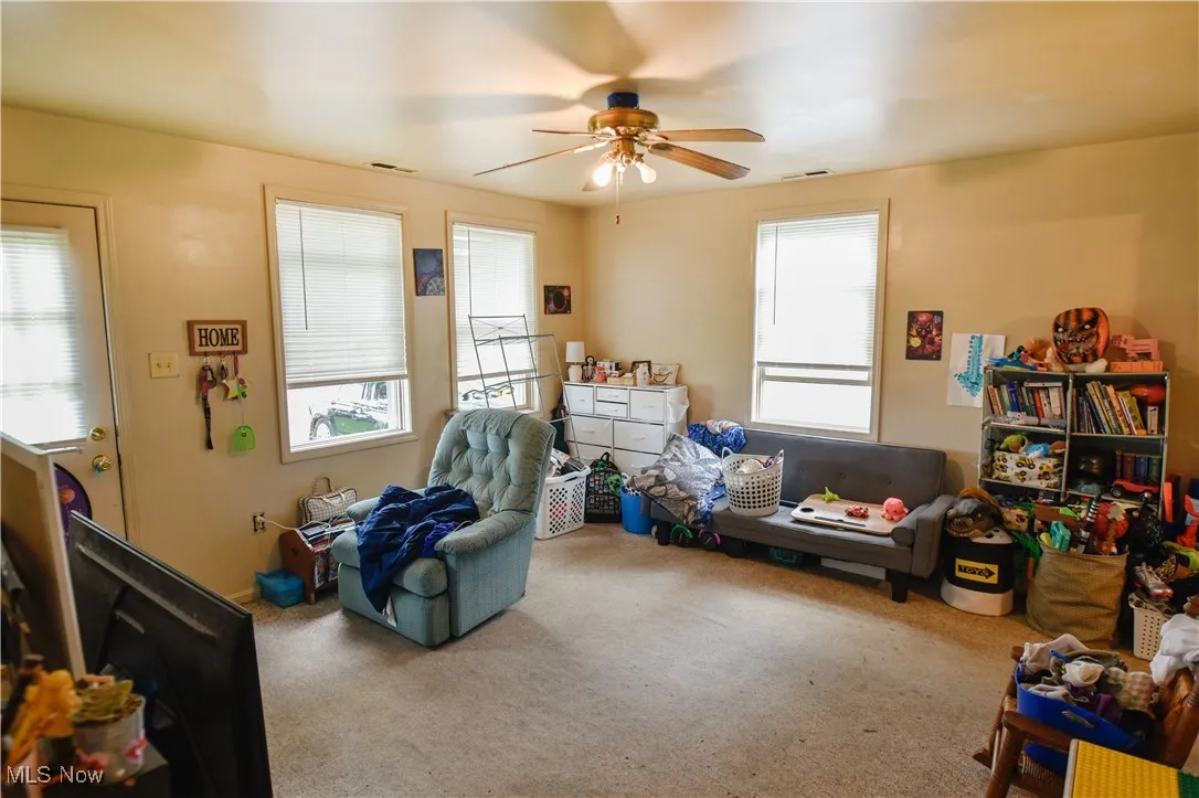Game room with a ceiling fan and carpet flooring