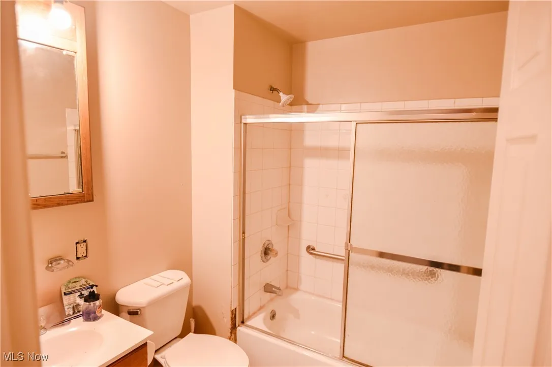 Bathroom featuring combined bath / shower with glass door and vanity