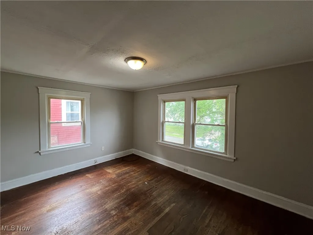 Unfurnished room with dark wood finished floors and plenty of natural light