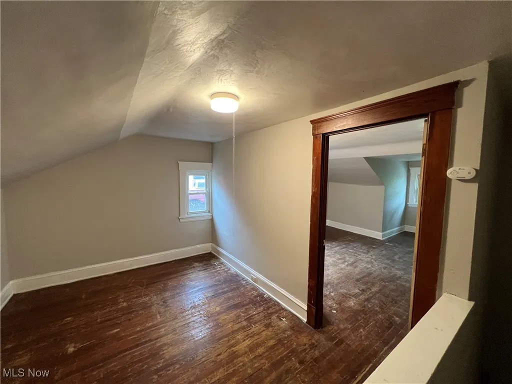 Bonus room with vaulted ceiling, dark wood finished floors, and a textured ceiling