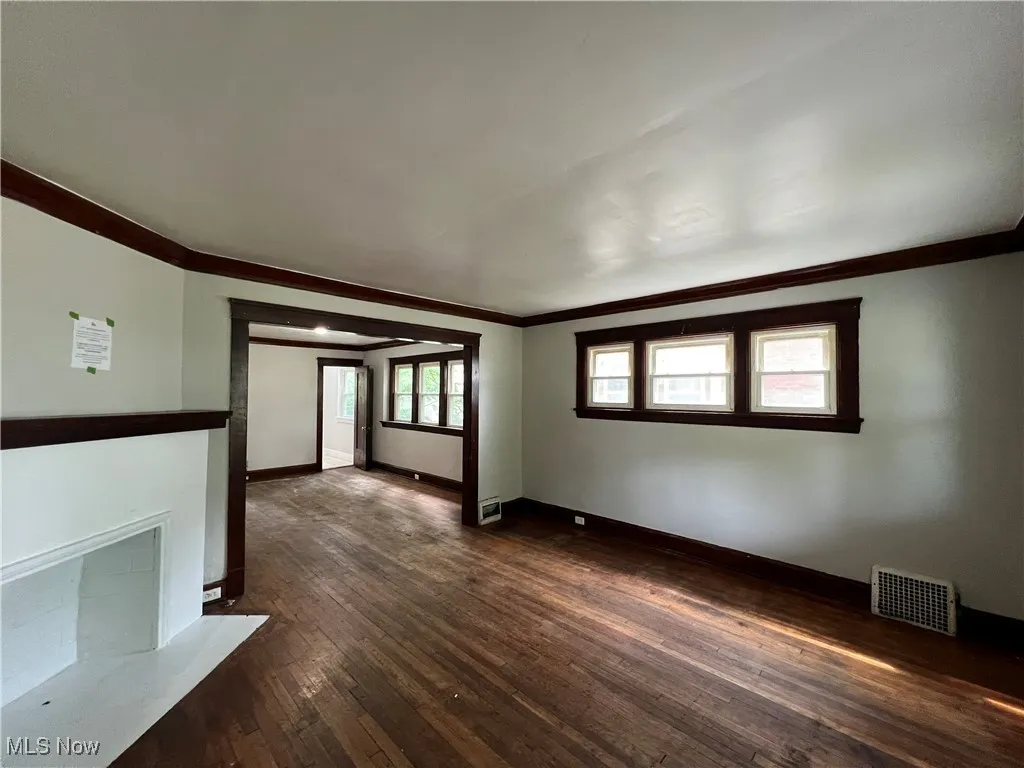 Spare room featuring crown molding and dark wood-style flooring