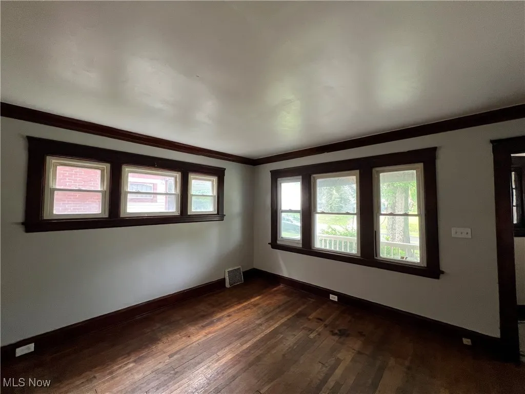 Empty room with dark wood-style floors and crown molding