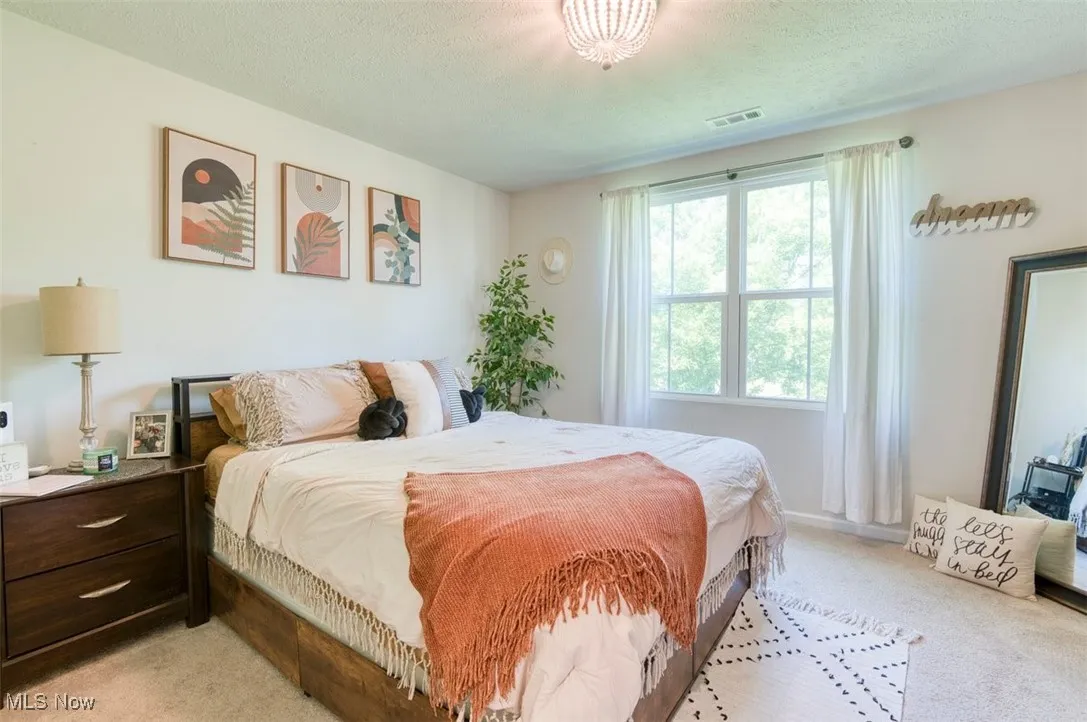 Bedroom featuring light colored carpet and a textured ceiling