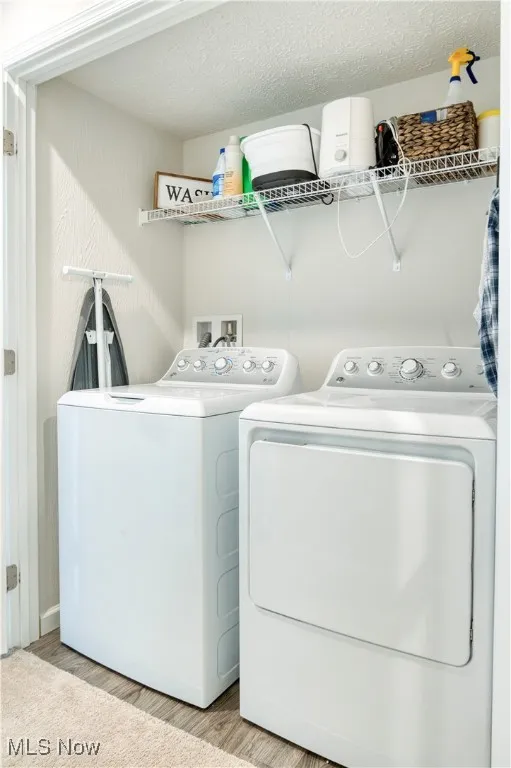 Laundry area with washing machine and clothes dryer and light wood-style flooring