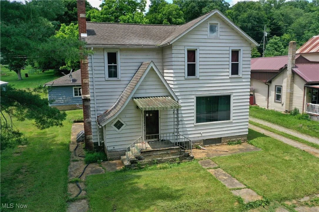 Traditional-style home with a front yard, a chimney, and a shingled roof