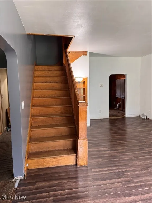 Stairway with arched walkways and wood finished floors