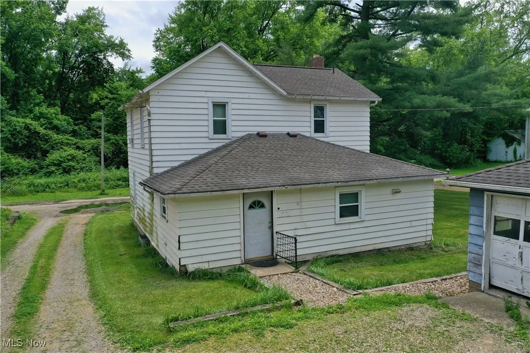 Back of property with roof with shingles and a yard