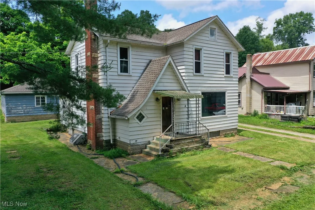 View of front facade featuring a front yard and a shingled roof
