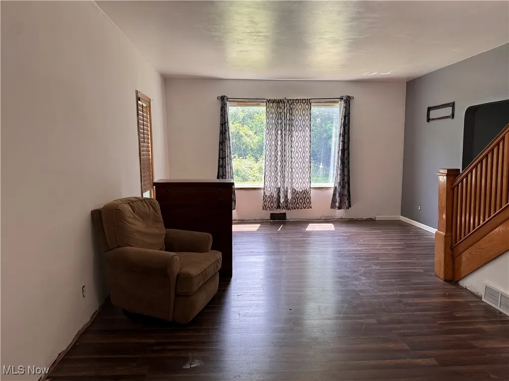 Living area with stairway and dark wood-style flooring