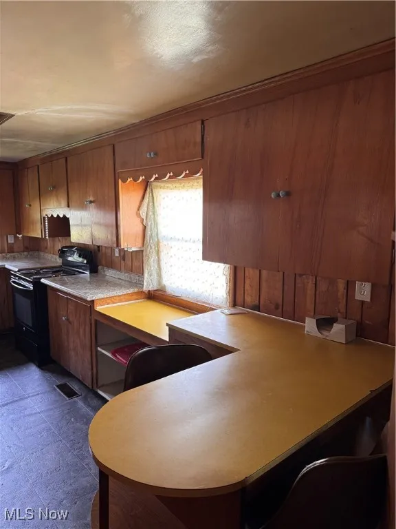 Kitchen with range, brown cabinets, and light countertops