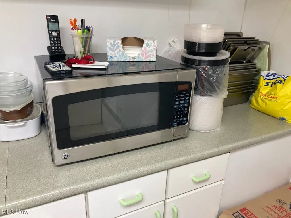 Kitchen view of stainless steel microwave, white cabinets, and light countertops
