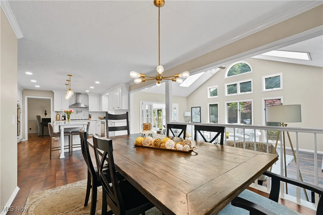 Dining space featuring a skylight, dark wood-style flooring, lofted ceiling, recessed lighting, and ornamental molding