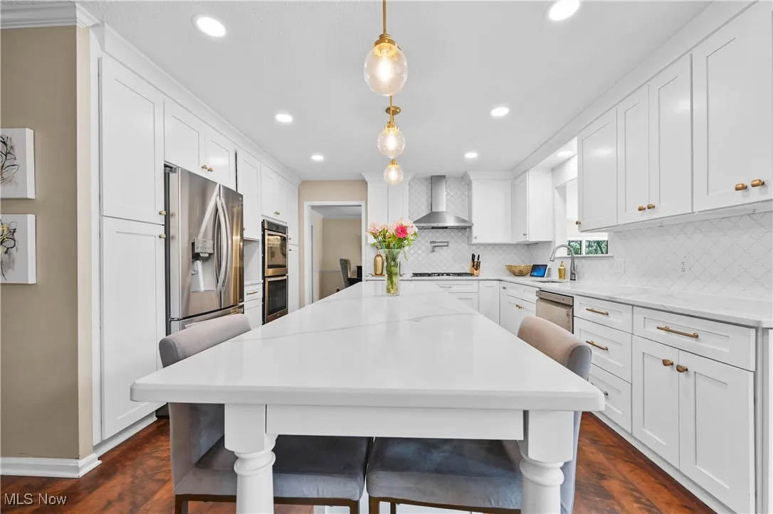 Kitchen featuring wall chimney exhaust hood, decorative backsplash, white cabinets, recessed lighting, and dark wood finished floors