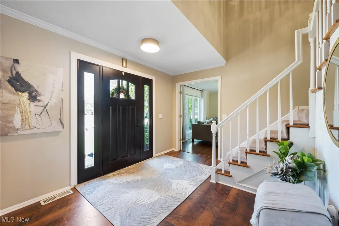 Entrance foyer featuring stairs, crown molding, and wood finished floors