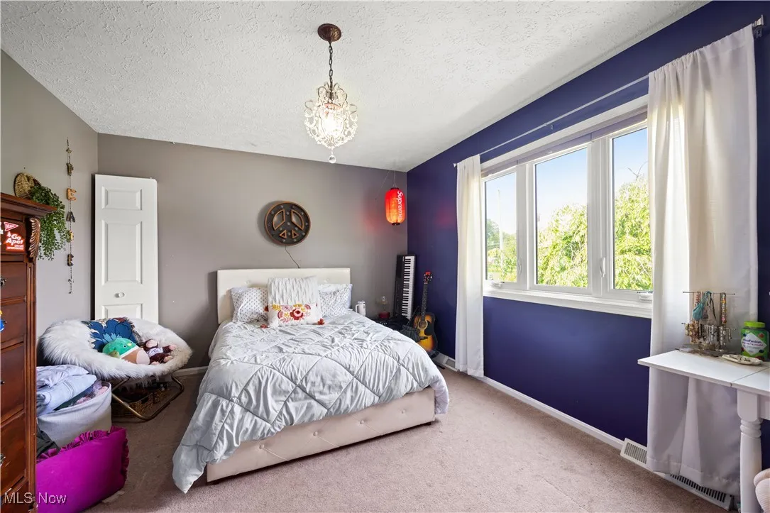 Bedroom with carpet flooring, a textured ceiling, and a chandelier