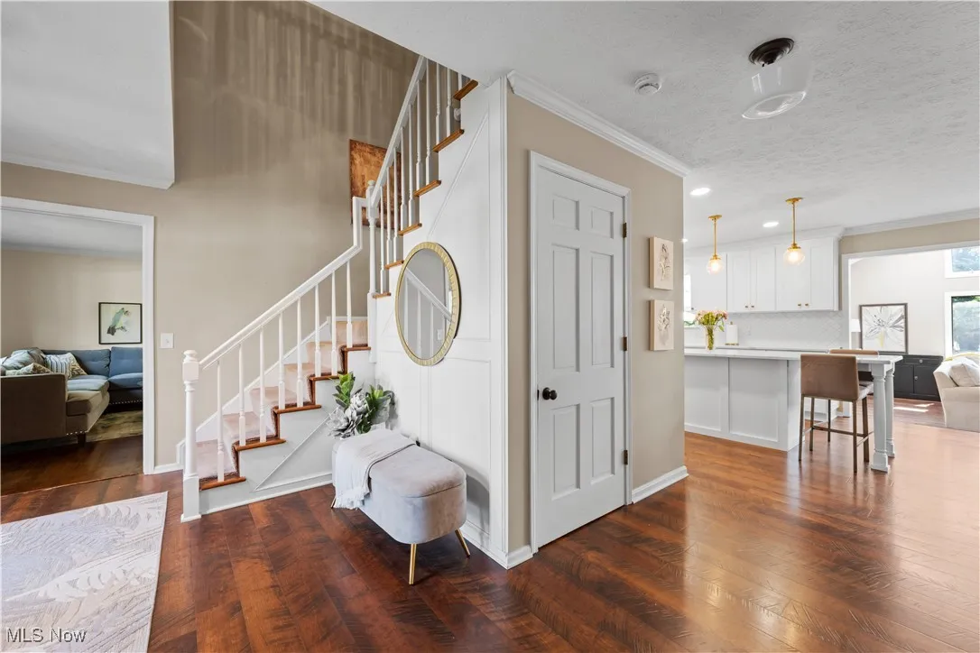 Entrance foyer featuring crown molding, stairway, dark wood-style flooring, and recessed lighting
