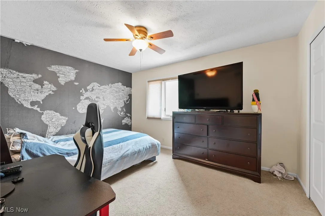 Bedroom with a ceiling fan, a textured ceiling, and light colored carpet