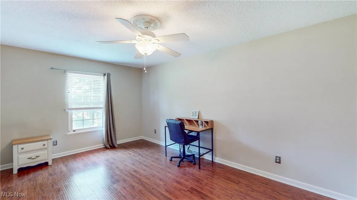 Home office featuring wood finished floors, ceiling fan, and a textured ceiling