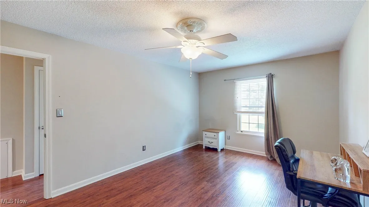 Office space featuring a ceiling fan, wood finished floors, and a textured ceiling