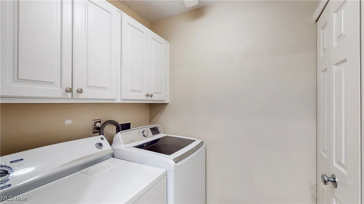 Laundry area with washing machine and dryer, cabinet space, a textured ceiling, and ceiling fan