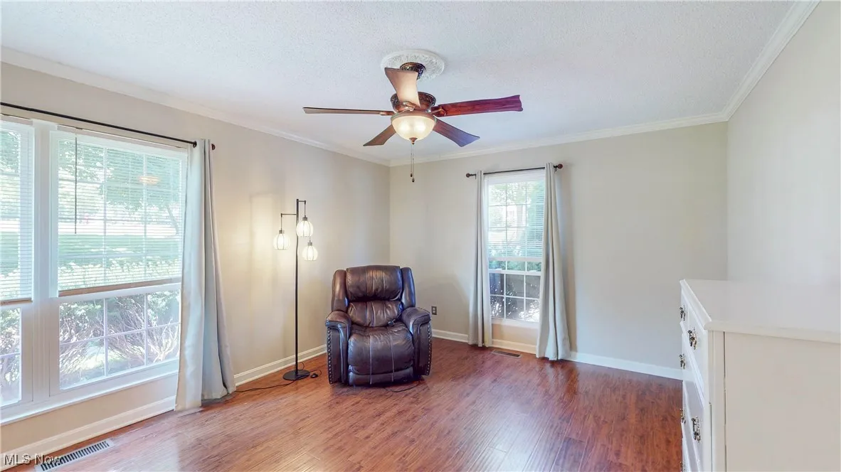 Living area with wood finished floors, ceiling fan, ornamental molding, and a textured ceiling