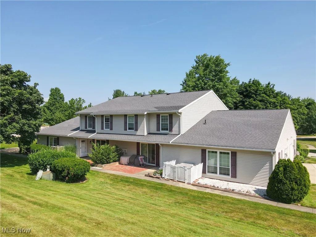 View of front of home featuring a front lawn, a patio area, and a shingled roof